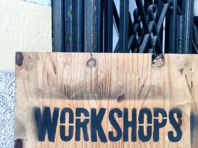 Wooden sign with Workshops painted on it with stencils